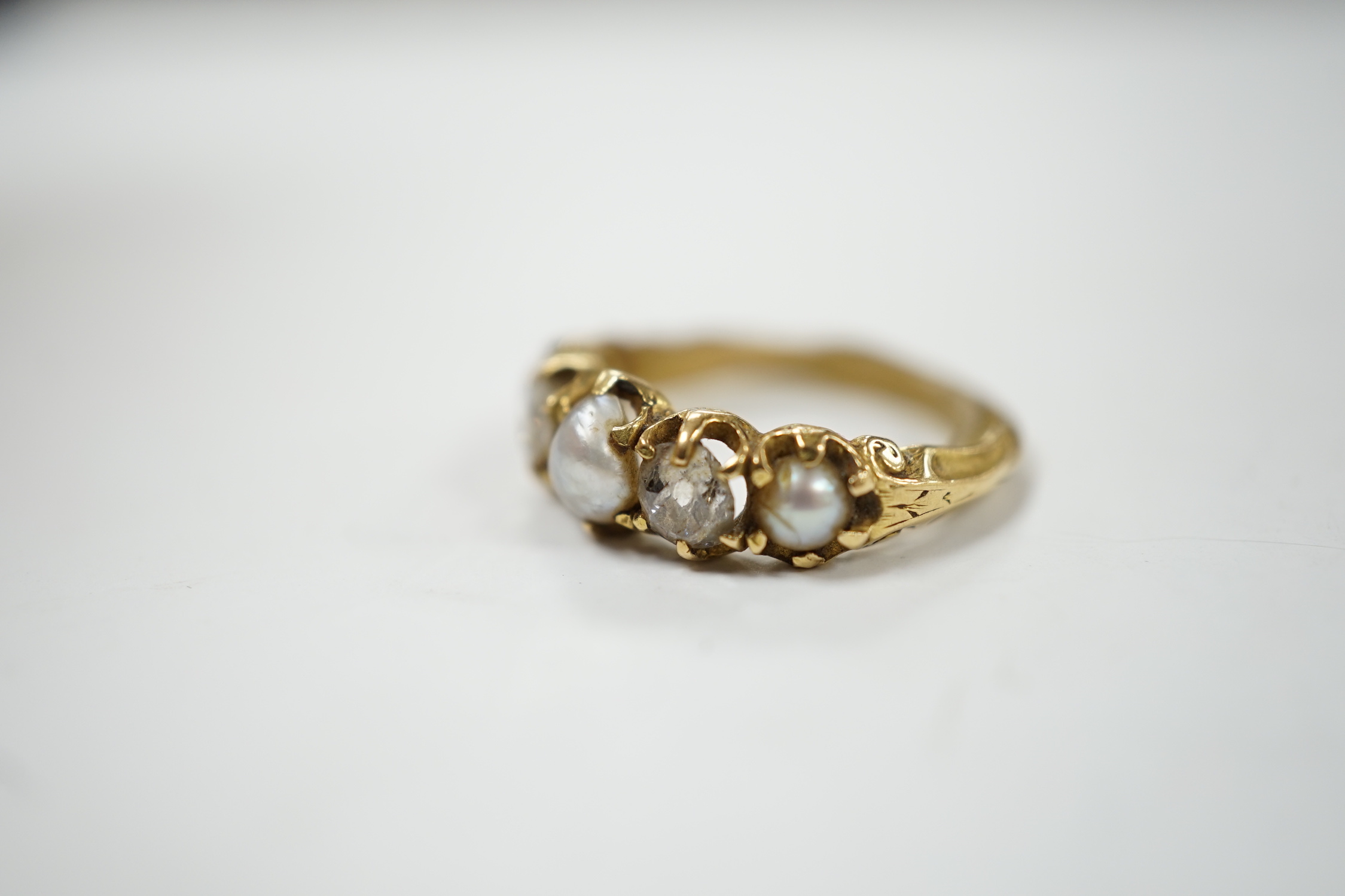 A late Victorian yellow metal and graduated three stone split pearl and two stone diamond set half hoop ring, with unusual wax? insert to the shank, size F, gross weight 3.2 grams.